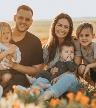 A family sitting in the grass with flowers.