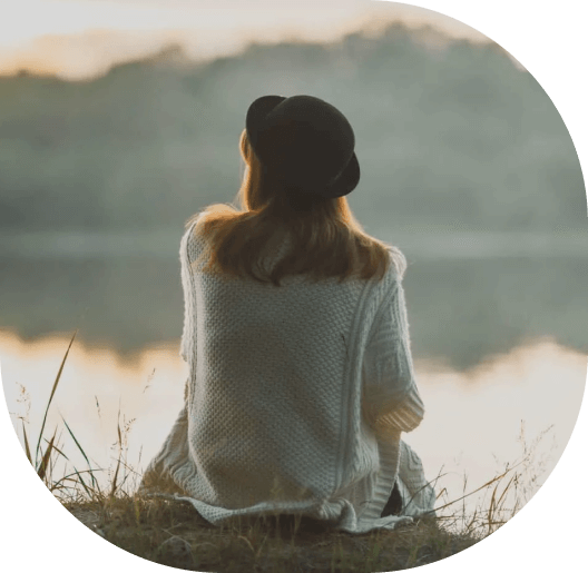 A woman sitting on the ground near water.